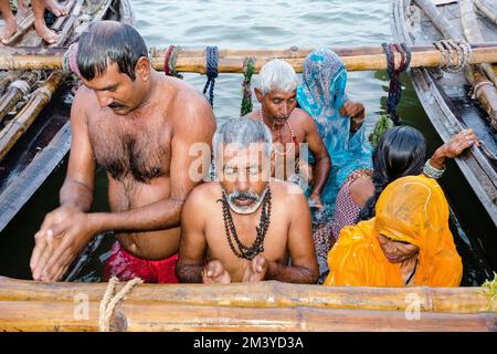 Pilger, die in Sangam, dem Zusammenfluss der heiligen Flüsse Ganges, Yamuna und Saraswati, ihr heiliges Bad ins Wasser nehmen Stockfoto