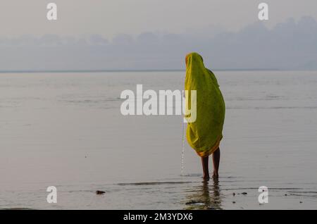 Alleinstehende Pilgerdame im Wasser bei Sangam, dem Zusammenfluss der heiligen Flüsse Ganges, Yamuna und Saraswati Stockfoto