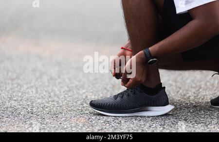 Läufer schwarz Mann tragen Uhr sitzend er versuchen Schnürsenkel laufen Schuhe Stockfoto