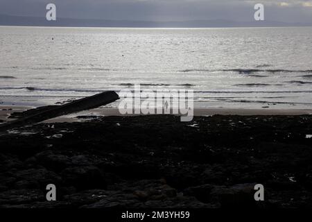 Mann Angeln vom Strand, Silhouette, Abend. Glänzende Meereslandschaft. Blick auf Porthcawl. Oktober 2022. Herbst. Stockfoto