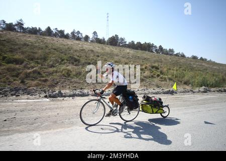 Istanbul, Türkei. 15. september 2012: Der Radfahrer auf einer langen Fahrt fährt auf der Straße mit einem Anhänger, der seine Ladung hinten transportiert. Stockfoto