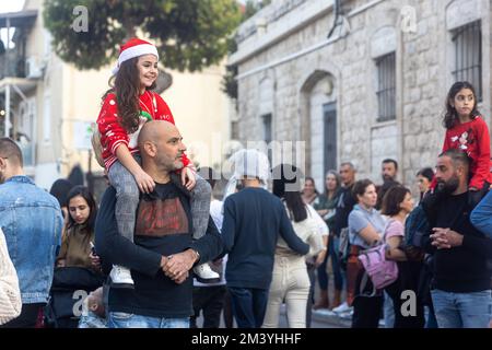 Haifa, Israel - 17. Dezember 2022 : Schüler der St. Elias Bischofsschule nimmt an der Weihnachtsparade in der deutschen Kolonie Teil. Die Zuschauer beobachten sie Stockfoto