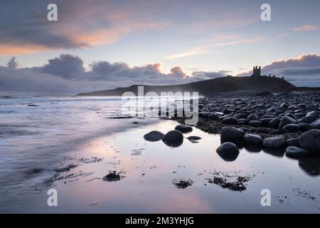 Sonnenaufgang über Dunstanburgh Castle. Embleton Bay, Alnwick, Northumberland, Großbritannien. 11. Dezember 2022 Foto von Richard Holmes. Stockfoto