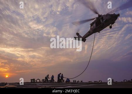 Arabischer Golf. 7.. Dezember 2022. Der Zerstörer USS die Sullivans (DDG 68) führt Hubschrauberbetankungsoperationen während des Fluges mit einem MH-60R Sea Hawk Hubschrauber durch, der der Helicopter Sea Combat Squadron (HSC) 26, Einheit 1, im Arabischen Golf, Dezember, zugewiesen wurde. 7. Die Sullivans werden in das US-Flottengebiet 5. entsandt, um die Sicherheit und Stabilität der Seeschifffahrt im Nahen Osten zu gewährleisten. (Kreditbild: © Kevin FRUs/USA Navy/ZUMA Press Wire Service) Stockfoto