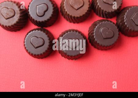 Schokoladenetui mit dem Symbol des Herzens. Schokoladenbonbons zum Valentinstag. Bonbon auf rotem Hintergrund mit Platz für Werbedrucke Stockfoto