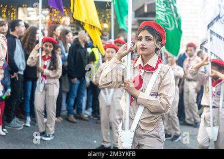 Haifa, Israel - 17. Dezember 2022 : Schüler der St. Elias Bischofsschule nimmt an der Weihnachtsparade in der deutschen Kolonie Teil. Die Zuschauer beobachten sie Stockfoto