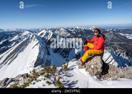 Skifahrer sitzen auf einem Felsen, auf dem Gipfel von Sonntagshorn, auf den schneebedeckten Gipfeln Hirscheck und Vorderlahnerkopf, Bergpanorama Stockfoto