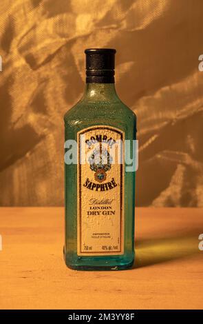 Eine vertikale Nahaufnahme einer Bombay Sapphire Gin-Flasche mit Wassertropfen auf dem Holztisch Stockfoto