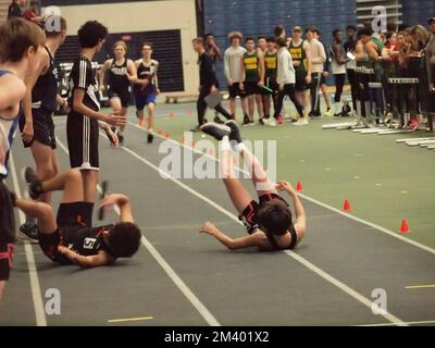 Läufer fallen während eines Schlagstößels in einer Highschool-Halle. Andere Mitbewerber werden sich nähern. Stockfoto