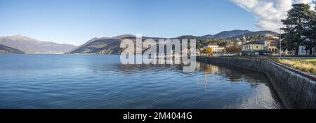 Extra Weitwinkelblick auf die Promenade am See in Luino mit den Bergen im Hintergrund Stockfoto