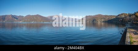 Extra Weitwinkelblick auf die Promenade am See in Luino mit den Bergen im Hintergrund Stockfoto