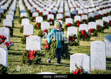 Arlington, Vereinigte Staaten Von Amerika. 17.. Dezember 2022. Arlington, Vereinigte Staaten von Amerika. 17. Dezember 2022. Während der 31. Kränze am America Day auf dem Arlington National Cemetery am 17. Dezember 2022 in Arlington, Virginia, hilft ein junges Mädchen dabei, Weihnachtskränze auf die Gräber eines gefallenen Soldaten zu stellen. Mehr als 30.000 Freiwillige platzieren 257.000 Kränze an jedem Grab des Nationalfriedhofs von Arlington und an anderen Orten im ganzen Land. Kredit: Elizabeth Fraser/US Army Foto/Alamy Live News Stockfoto