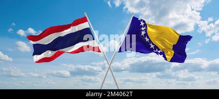 Zwei gekreuzte Flaggen Bosnien und Herzegowina und Thailand winken im Wind am bewölkten Himmel. Beziehungskonzept, Dialog, Reisen zwischen zwei Ländern. Stockfoto