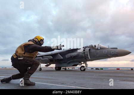 Norfolk, Usa. 06.. Dezember 2022. EIN US-AMERIKANISCHER Navy Yellow Weste signalisiert ein Kampfflugzeug des Marine Corps AV-8B Harrier II mit dem Ace of Pades of Marine Attack Squadron 231 zum Start vom Flugdeck des Amphibienschiffs USS Kearsarge der Wasp-Klasse auf dem Atlantik, 16. Dezember 2022 nahe Norfolk, Virginia. Kredit: CPL. Christian Cortez/US Marines Photo/Alamy Live News Stockfoto