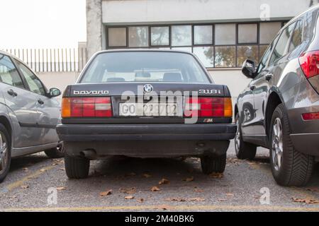 Hinter dem schwarzen BMW 318i (1989) Parken auf einem Stadtparkplatz. Stockfoto