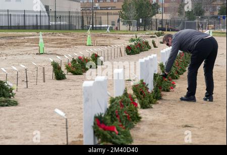 St. Louis, Usa. 17.. Dezember 2022. Besucher eines Grabes auf dem Jefferson Barracks National Cemetery in St. Louis, legt einen Weihnachtskranz auf einen der kürzlich begrabenen Veteranen in einer neu geschaffenen Gegend während Kränze in Amerika am Samstag, den 17. Dezember 2022. 3.702 teilnehmende Orte wurden in die National Kränze am America Day aufgenommen. Mehr als zwei Millionen Freiwillige, von denen ein Drittel Kinder waren, halfen dabei, mehr als 2,7 Millionen Veteranenkränze auf Grabsteinen der Gefallenen im ganzen Land zu platzieren. Foto: Bill Greenblatt/UPI Credit: UPI/Alamy Live News Stockfoto