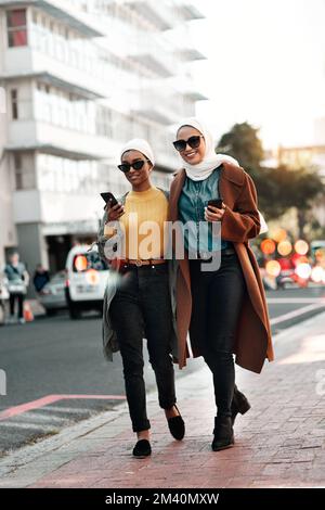Reisen ist mehr wert, als Geld jemals sein wird. Aufnahme von zwei jungen attraktiven Frauen in voller Länge, die beim Durchgehen eine Sonnenbrille und ein Kopftuch tragen Stockfoto