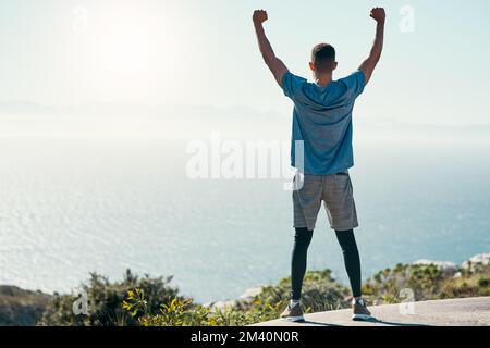 Du kannst alles tun, was du willst. Rückansicht eines jungen Mannes, der seinen Sieg nach einem Lauf im Freien feiert. Stockfoto