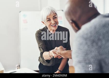 Ich bin froh, dass du dich entschieden hast, dich uns anzuschließen. Zwei fröhliche Geschäftsleute, die sich tagsüber im Büro in Absprache die Hände schütteln. Stockfoto