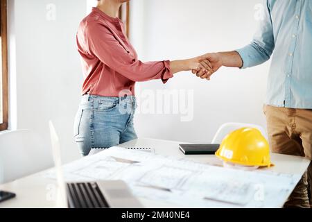 Es ist mir ein Vergnügen, mit Ihnen Geschäfte zu machen. Zwei unbekannte Geschäftsleute, die sich über Baupläne im Büro einig waren. Stockfoto