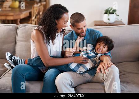 Wir lieben es, ihn glücklich zu sehen. Ein Junge, der von seinen Eltern gekitzelt wird. Stockfoto