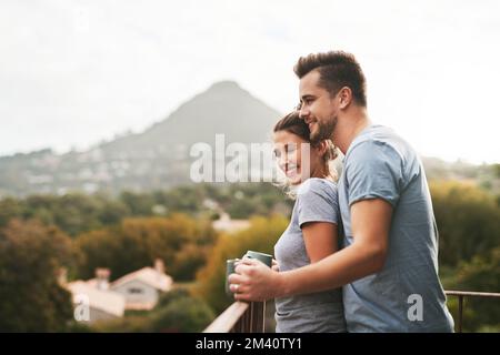 Das ist unser glücklicher Ort. Ein liebevolles junges Paar, das morgens auf dem Balkon zu Hause Kaffee trank. Stockfoto