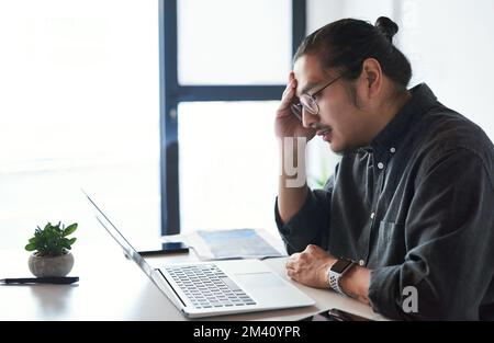 Diese Fristen werden mein Ende sein. Ein gutaussehender junger Geschäftsmann, der gestresst aussieht und Kopfschmerzen bei der Arbeit hat. Stockfoto