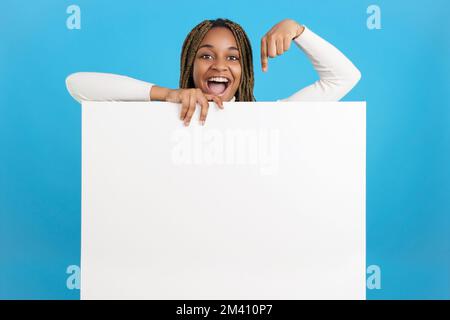 Glückliche afrikanerin, die auf ein Schild mit Leerzeichen zeigt Stockfoto