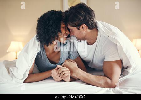 Bedeckt von Liebe und Glück. Ein liebevolles junges Paar, das eine schöne Zeit zusammen in seinem Schlafzimmer zu Hause verbringt. Stockfoto
