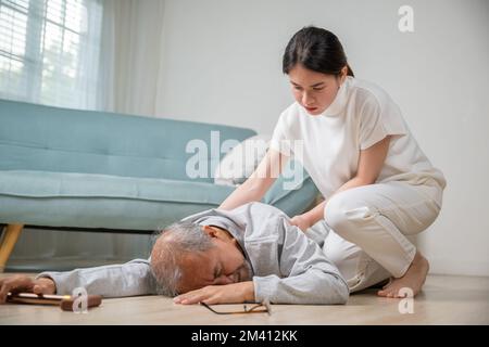 Eine junge Frau aus Asien, die ihren Vater schläft, nachdem sie auf den Boden gefallen ist Stockfoto