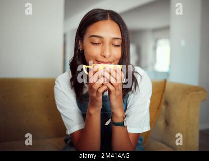 Kaffee, Frau und Morgengetränk auf einem Wohnzimmersofa, beruhigend, entspannt und friedlich. Haus, Tee und natürliches Aroma einer Person, die und riecht Stockfoto