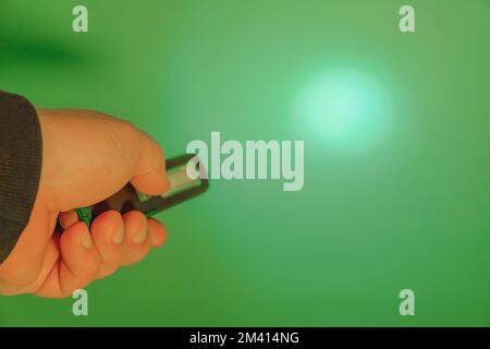 Taschenlampe mit LED in der Hand. Leuchtet auf grünem Hintergrund. Speicherplatz kopieren Stockfoto