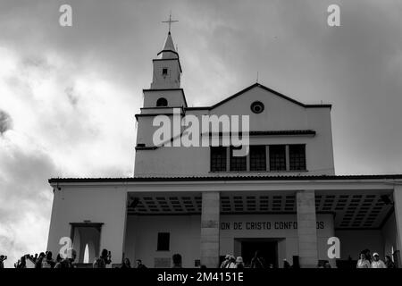 Eine Graustufenaufnahme der Kirche Monserrate auf bewölktem Hintergrund mit einer Menschenmenge davor Stockfoto