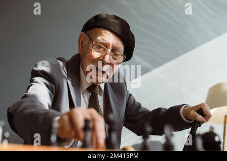 Porträt eines seriösen alten Mannes, der im Zimmer Schach spielt Stockfoto
