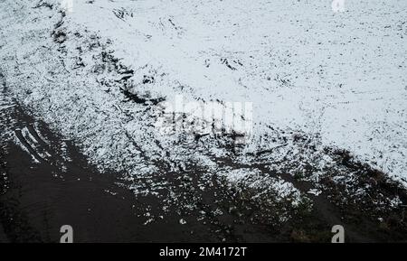 Ein Blick aus der Vogelperspektive auf eine im Winter mit Schnee bedeckte Landschaft an einem Fluss Stockfoto