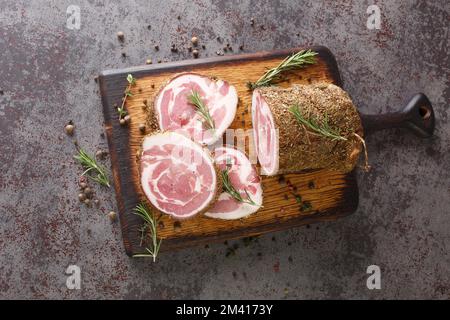 Italienischer traditioneller Bacon Pancetta auf einem Schneidebrett, Nahaufnahme auf dem Tisch. Horizontale Draufsicht von oben Stockfoto