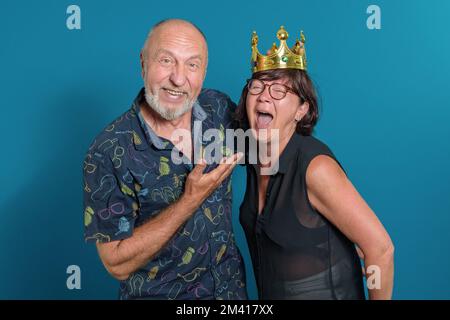 Glücklich zusammen. Reifes Paar, das lacht. Lange Ehe in verliebten, lustigen Momenten. Krone auf dem Kopf seiner Frau. Stockfoto