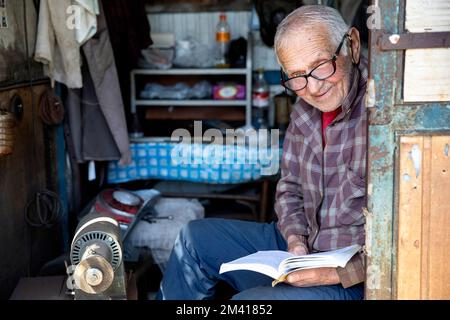 Interessante Szenen vom lokalen täglichen Markt in Ozurgeti, in der Nähe der Küste des Roten Meeres, Mann, ein Verkäufer, der während des Verkaufs ein Buch liest, Georgia Stockfoto