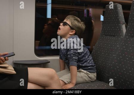 Das Kind langweilt sich im Zug. Der Junge weiß nicht, was er auf einer Reise tun soll Stockfoto