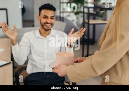 Ein junger Hindu-Mann ist dabei, Kerzen auf einem Kuchen auszublasen und sich während einer Geburtstagsfeier mit Kollegen etwas zu wünschen. Kollegen feiern eine Geburt Stockfoto