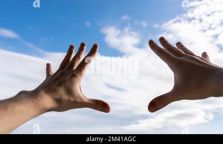 Hände eines Mannes, der zum Himmel greift. Stockfoto