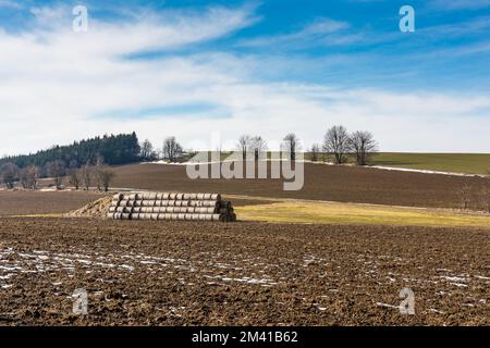 Strohballen und Gülle auf dem Feld. Frühlingsfelder und Vorbereitung auf die Landwirtschaft. Typisch tschechisches Land, Bäume und blauer Himmel. Stockfoto