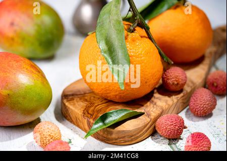 Ein Stillleben mit Lychees-Tangerinen und Mangos auf dem schäbigen Tisch Stockfoto