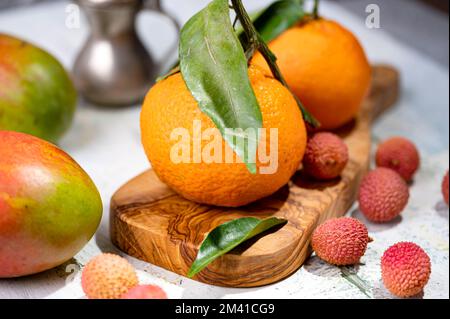 Ein Stillleben mit Lychees-Tangerinen und Mangos auf dem schäbigen Tisch Stockfoto