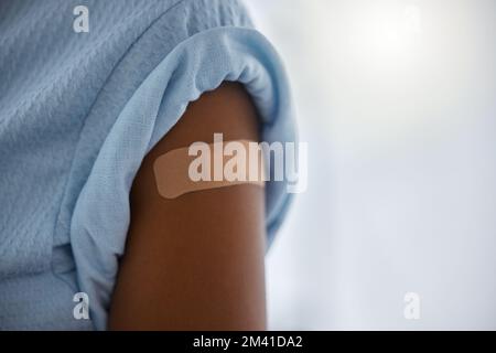 Covid, Impfstoff und Pflaster am Arm eines Patienten in einem Krankenhaus nach einer Auffrischimpfung zur Heilung oder Behandlung. Compliance, Corona-Virus und Gesundheitswesen Stockfoto