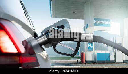 Nahaufnahme eines Brennstoffzellenwagens mit angeschlossener Wasserstoffbetankungsdüse auf dem Hintergrund einer H2-Tankstelle. Sauberes Mobilitätskonzept Stockfoto