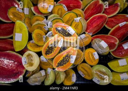 Cantaloupe Melone, Wassermelone und Papaya, halbiert verpackt in Plastikfolie ausgestellt und in Euro zum Verkauf im Supermarkt Kühlschrank, Draufsicht, REA Stockfoto