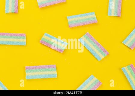 Viele bunte süße Süßigkeiten auf gelbem Hintergrund. Süßes Essen als Nachtisch. Platz für Text. Draufsicht. Stockfoto