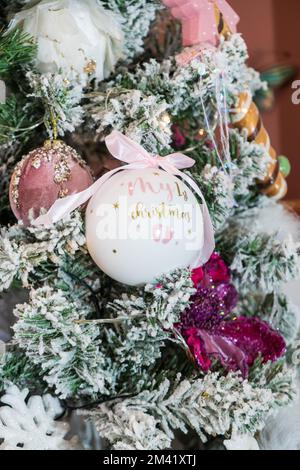 Weiß Mein erstes Weihnachtsball-Ornament hängt an einem Weihnachtsbaum. Neue Life Christmas- und Silvester-Konzepte. Stockfoto