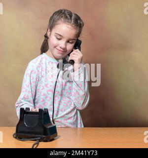 Das Teenager-Mädchen wählt eine Nummer auf einem alten Telefon. Retro-Porträt eines Mädchens. Quadratisches Format Stockfoto